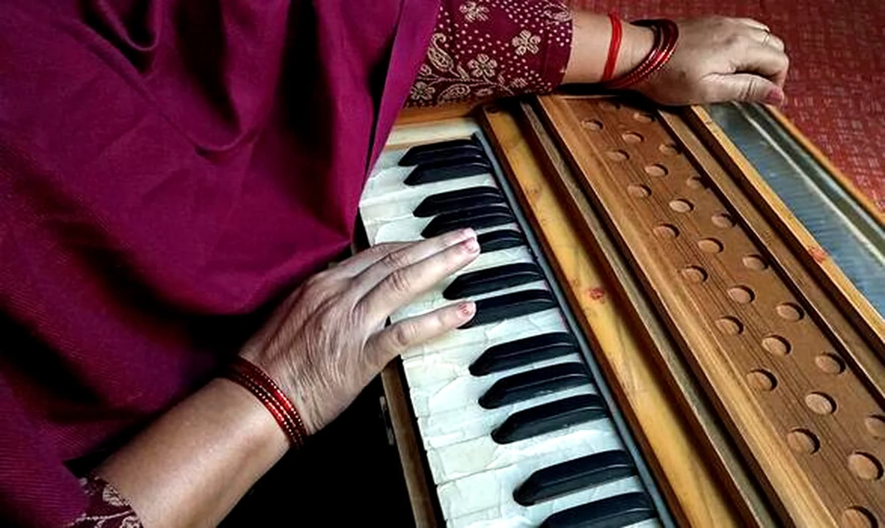 Mani di donna sulla tastiera di un harmonium indiano