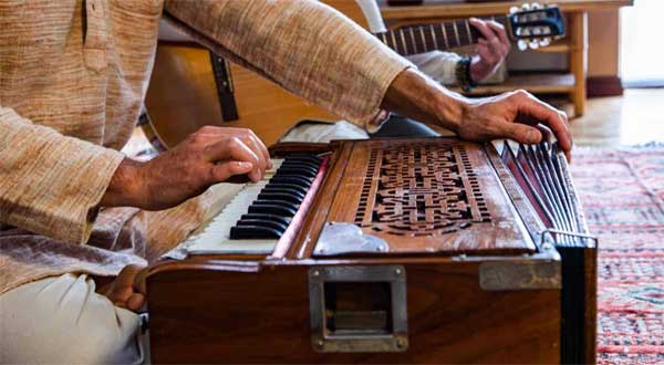 Uomo che suona l'harmonium indiano — pratica del Gayatri Mantra